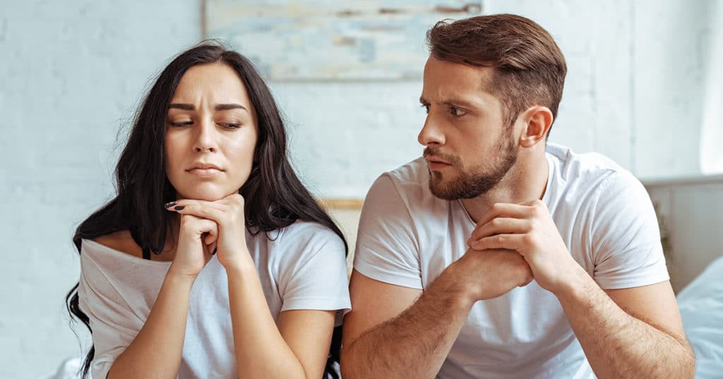 Man sitting next to and looking at woman in consternation